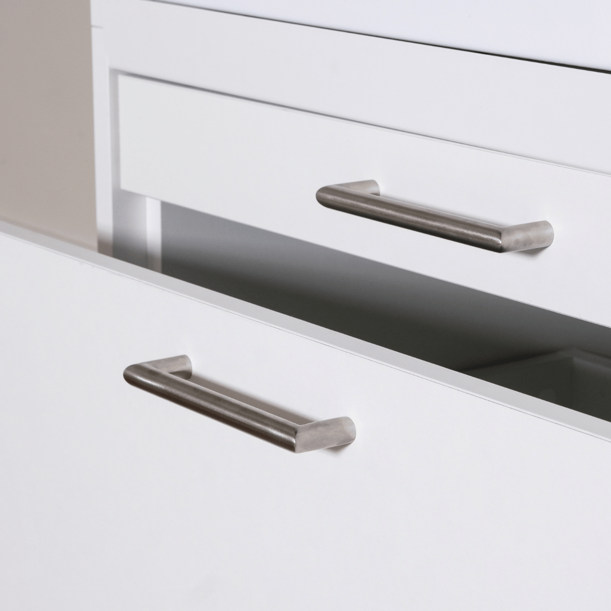 Matte silver metal cabinet handles with rounded edges on white drawers, modern minimalist style.