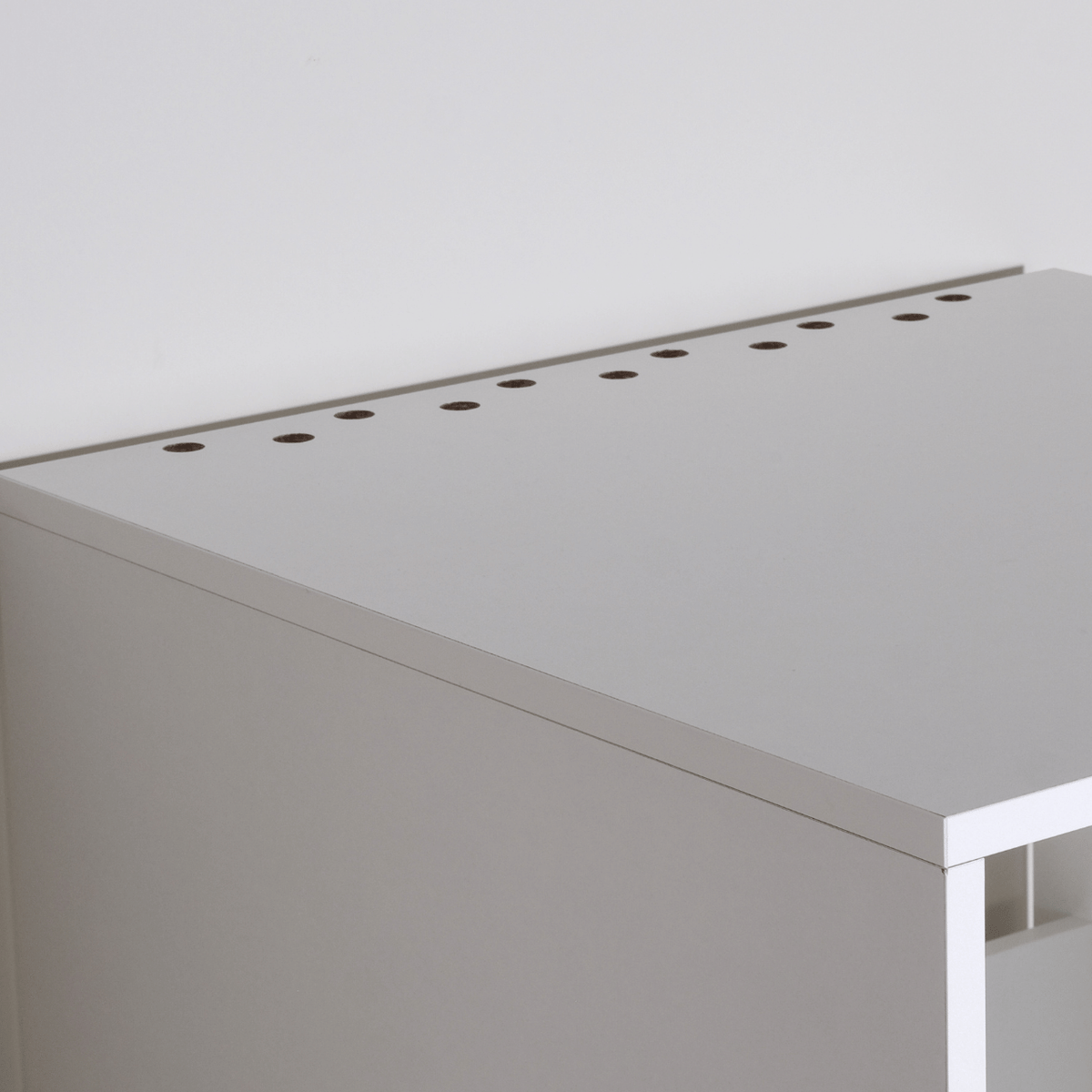 Metal drawer slide rail and white wooden cabinet corner with mounting bolt on wood floor background.