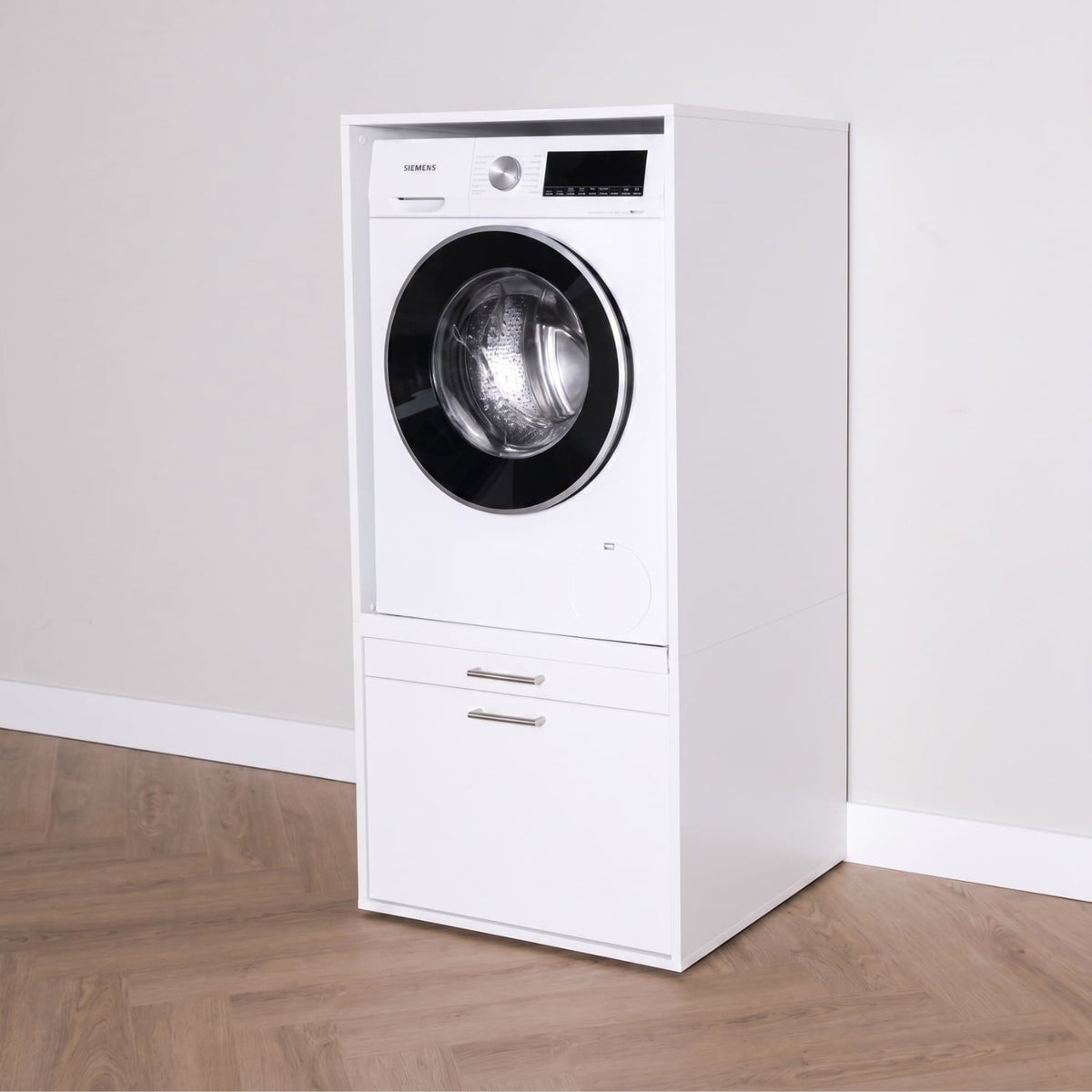 White front-loading washing machine integrated into a white cabinet with bottom drawer and silver handles.