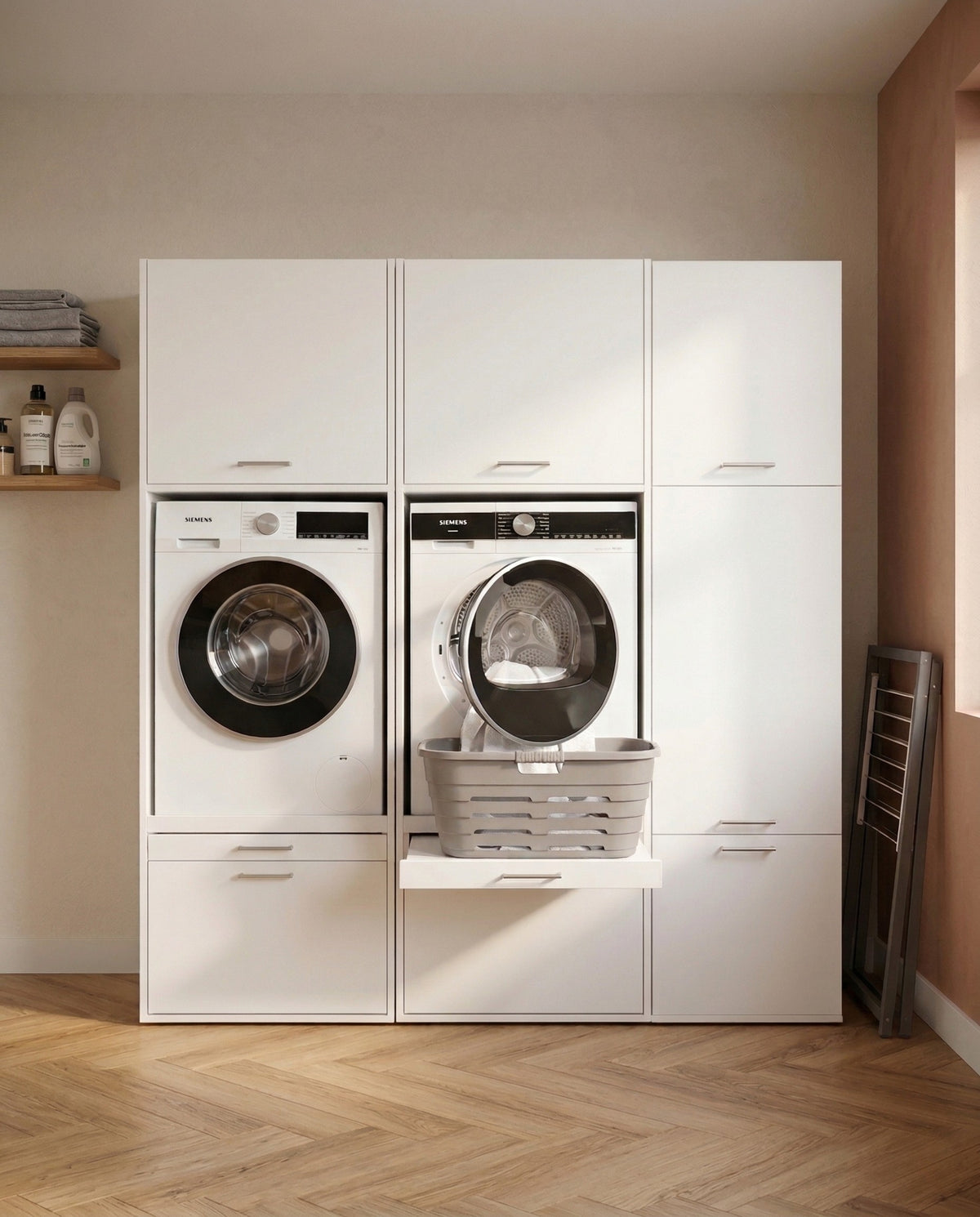 White built-in laundry cabinet with front-loading washer and dryer, one dryer door open with laundry basket inside.