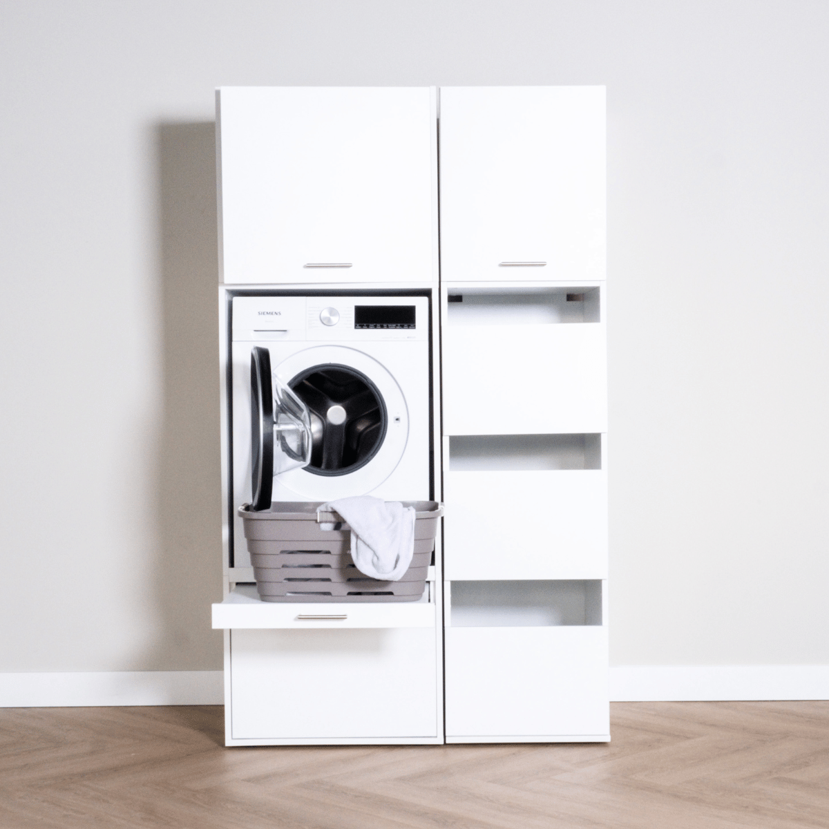 White freestanding laundry unit with front-load washing machine, open shelves, and storage drawers.